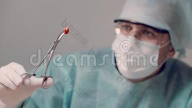 医生拿着带<strong>医疗器械</strong>的红色药片，检查药片。